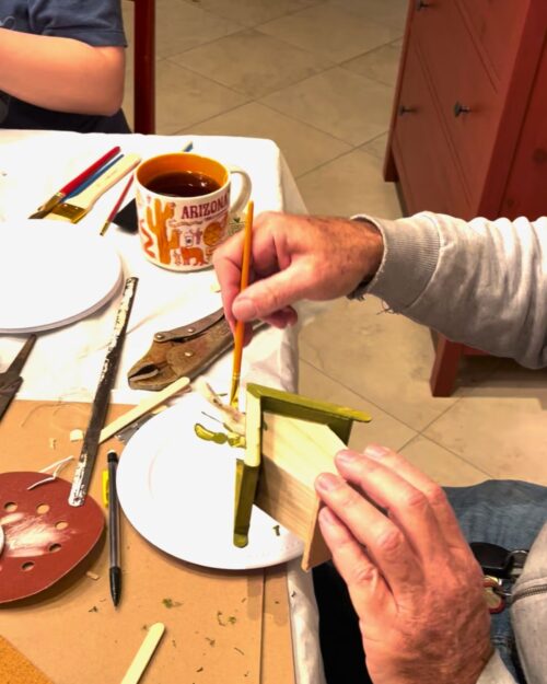 painting the eaves of a birdhouse green.