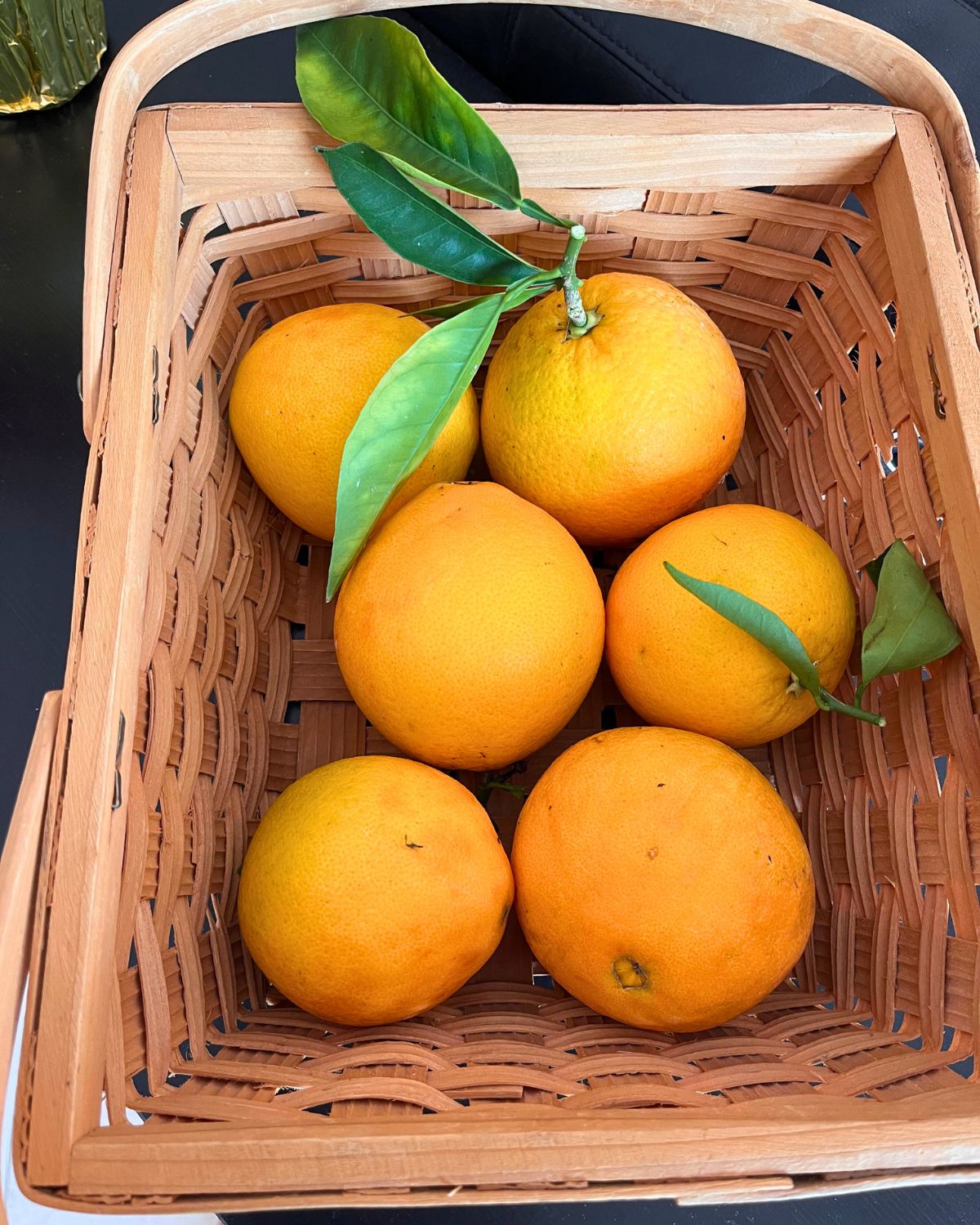 basket of oranges with leaves attached.