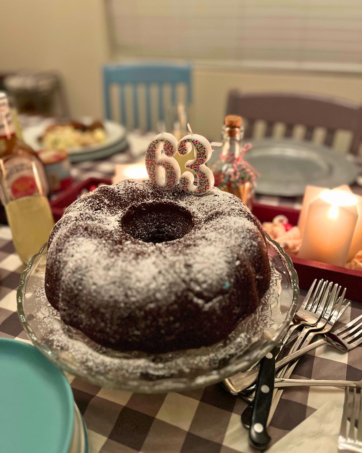 chocolate bundt cake with 63 candles on table set for dinner.