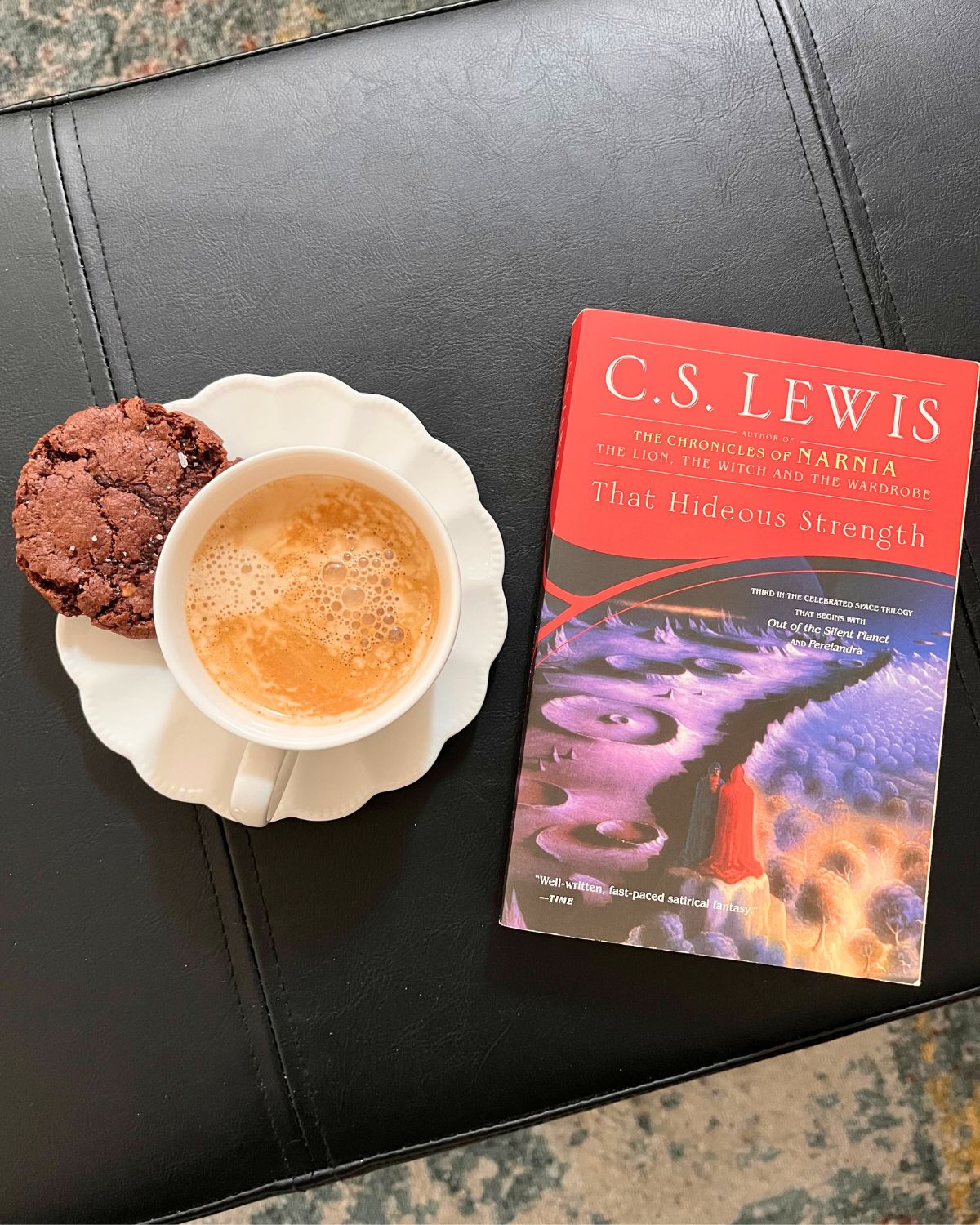 cup of coffee and cookie next to paper copy of that hideous strength.