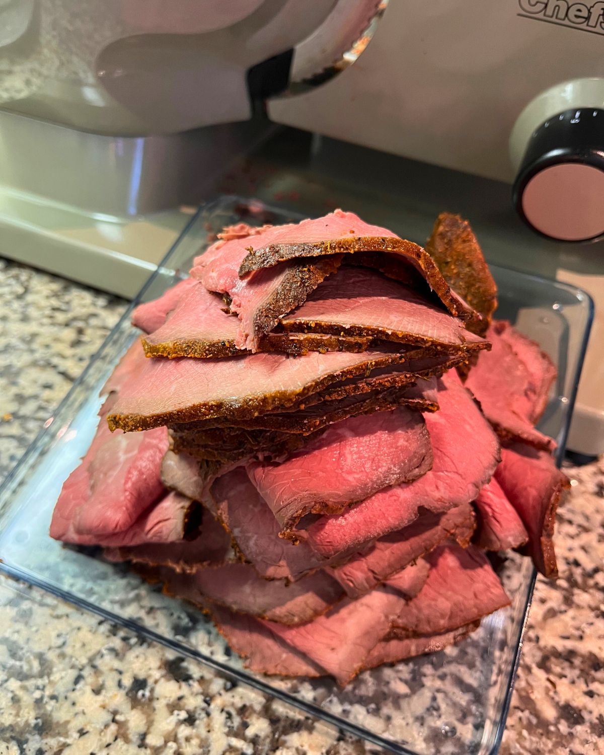 sliced roast beef next to electric food slicer.