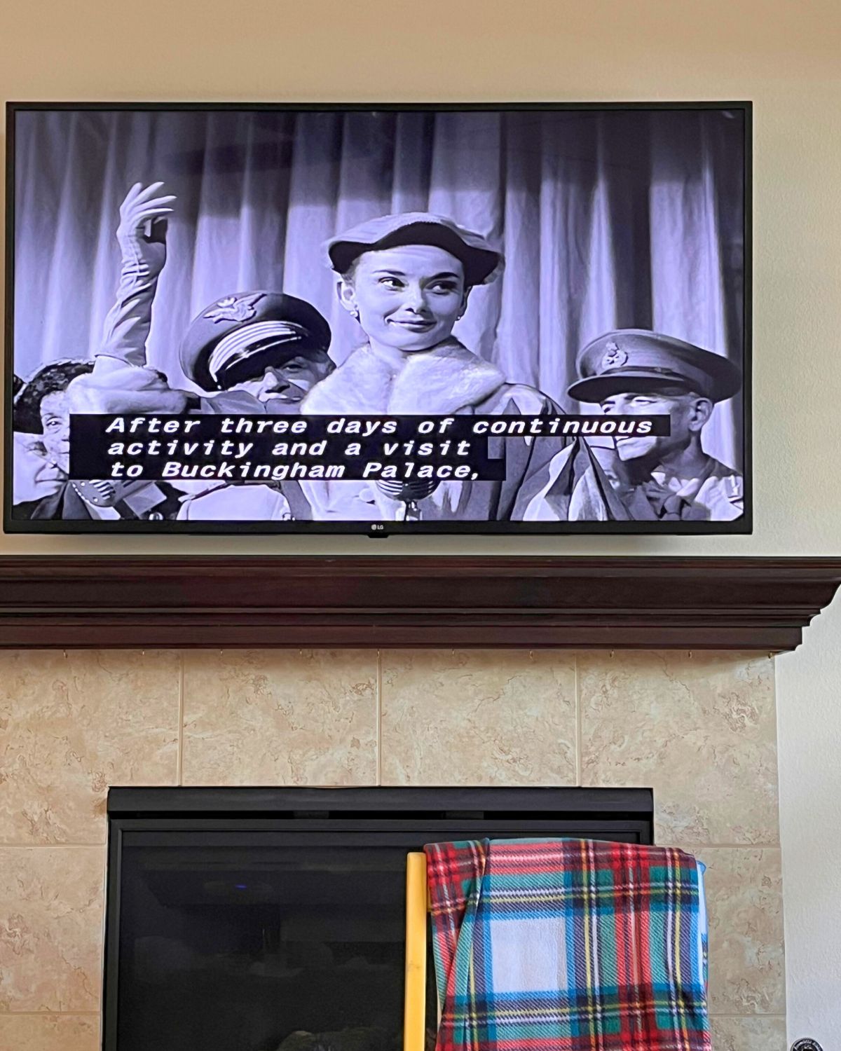 screenshot of Roman Holiday film on tv on wall above fireplace.