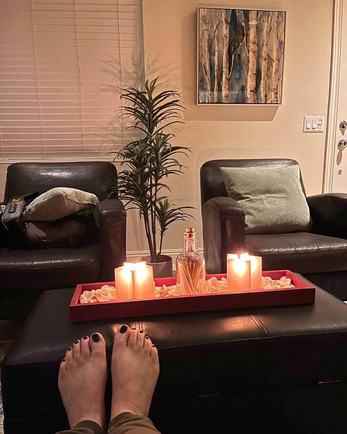 feet propped on ottoman where candles are lit.