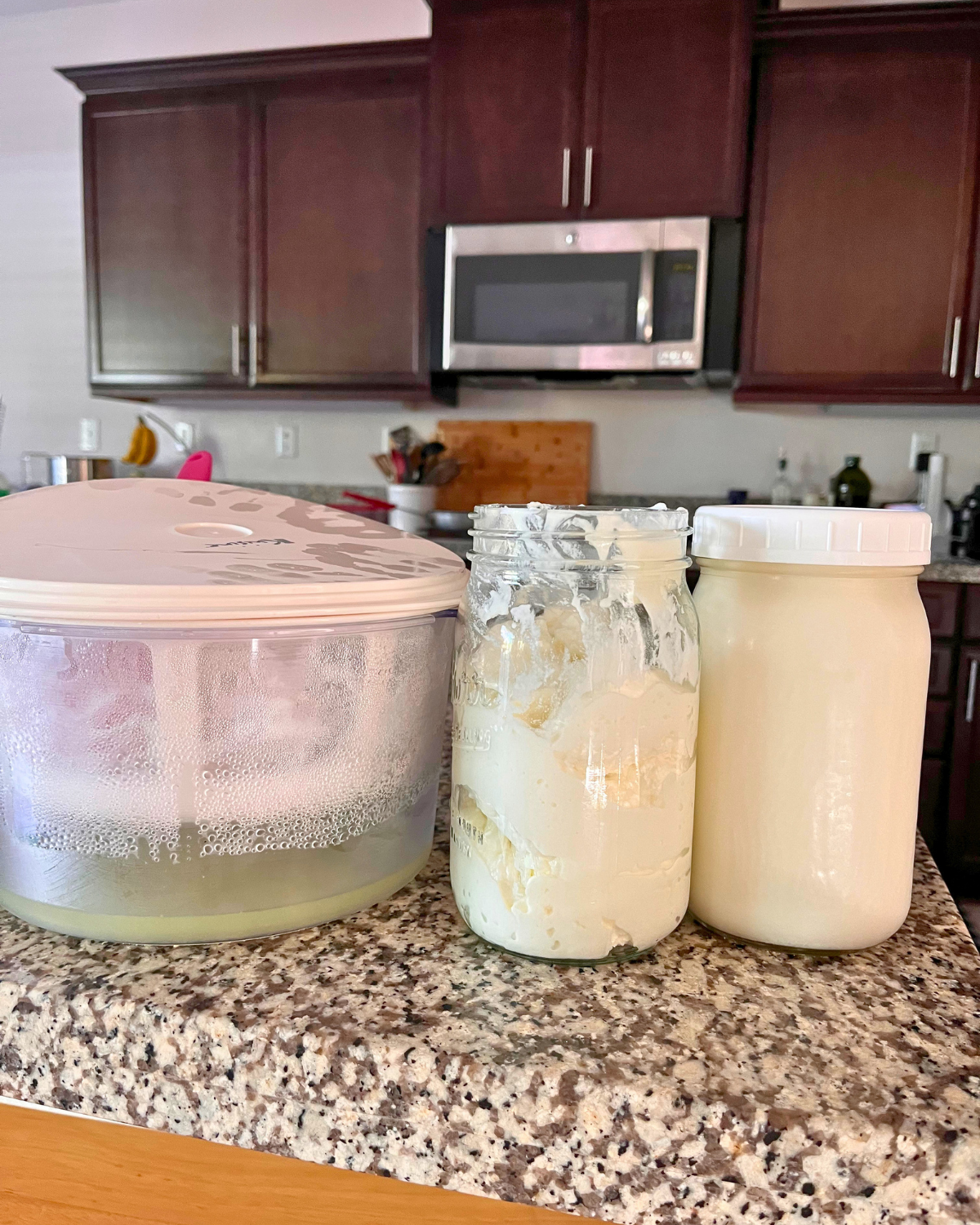 homemade yogurt in jars next to strainer.