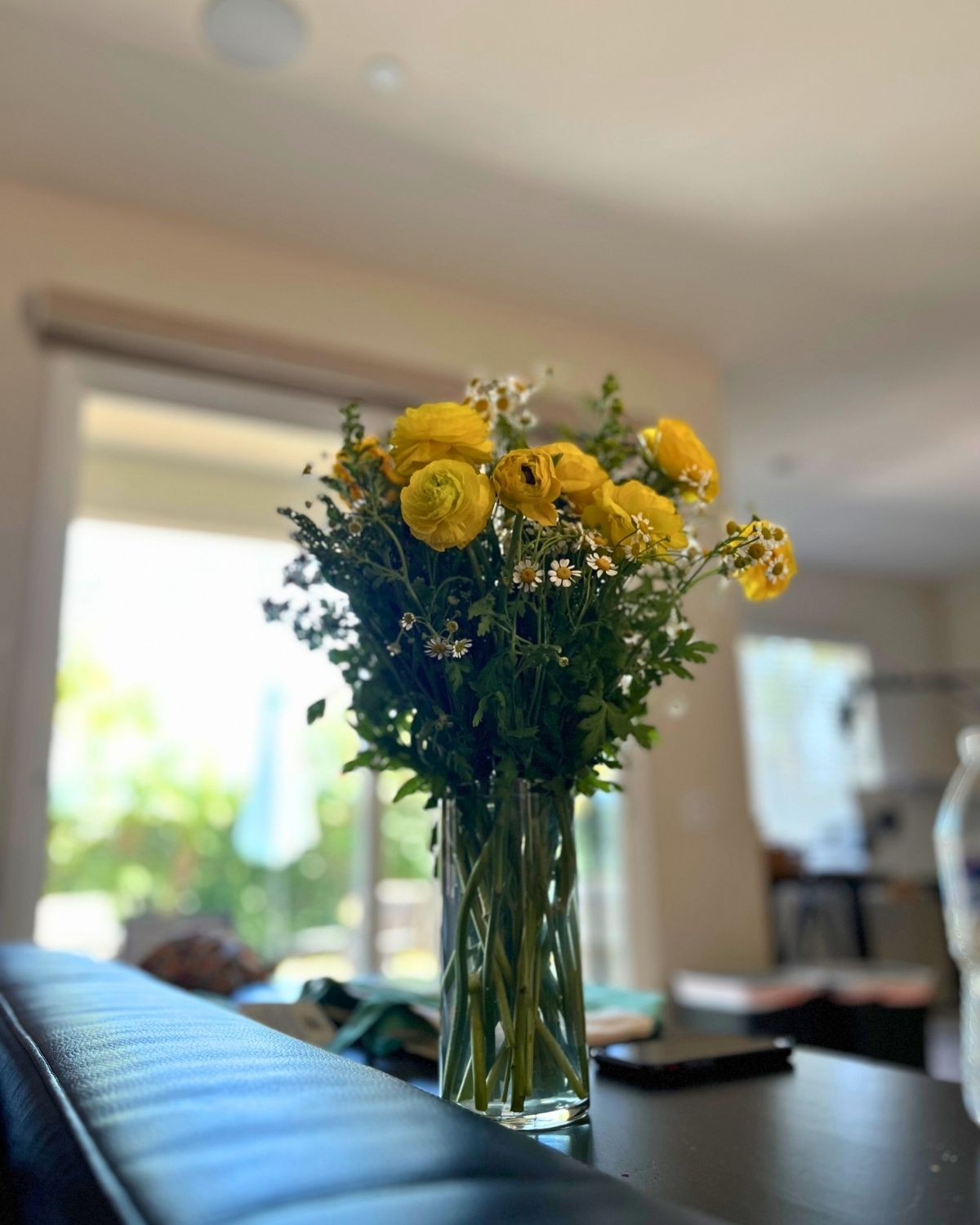 bouquet of yellow flowers on console behind couch.