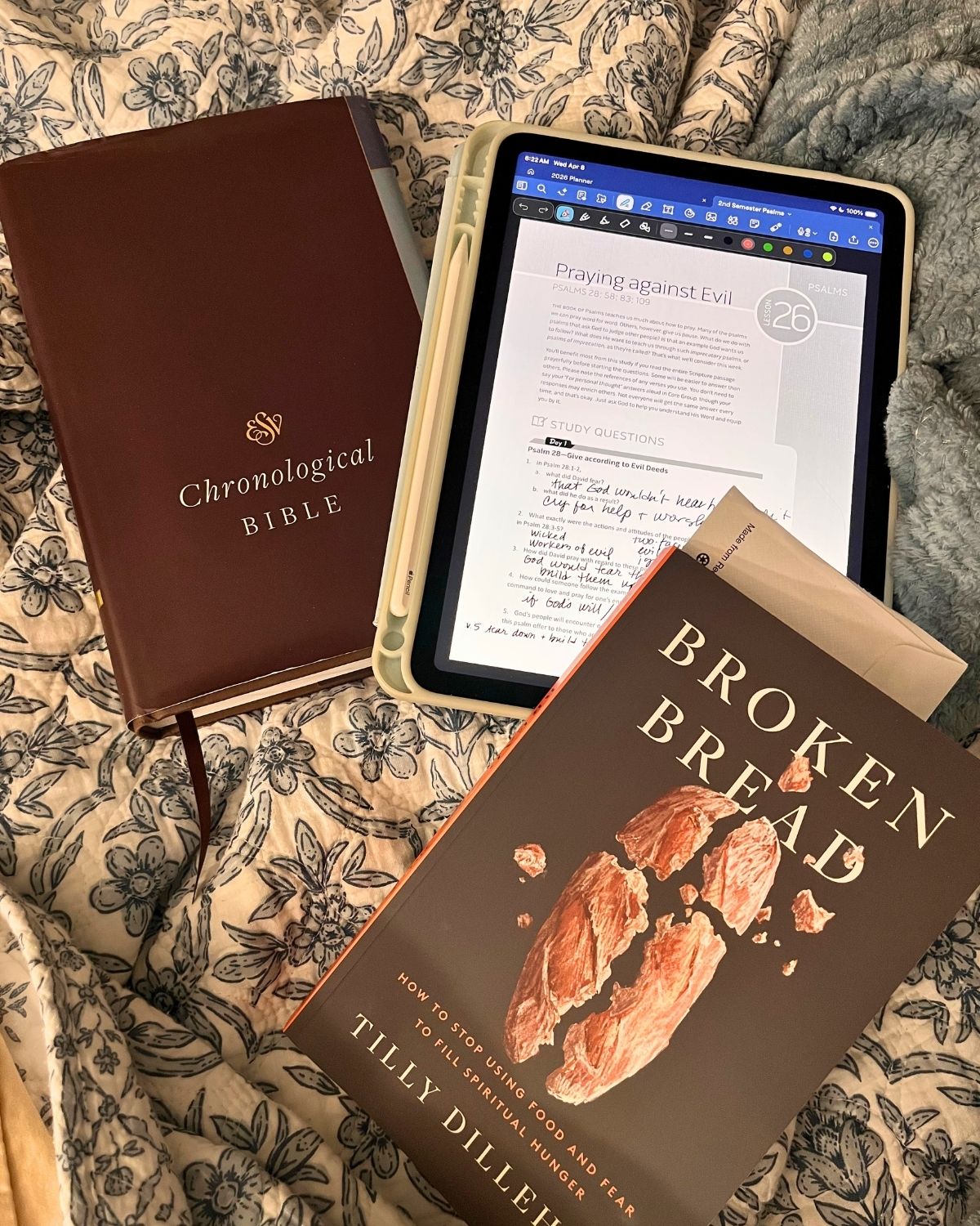 bedspread of books, bible, and iPad.