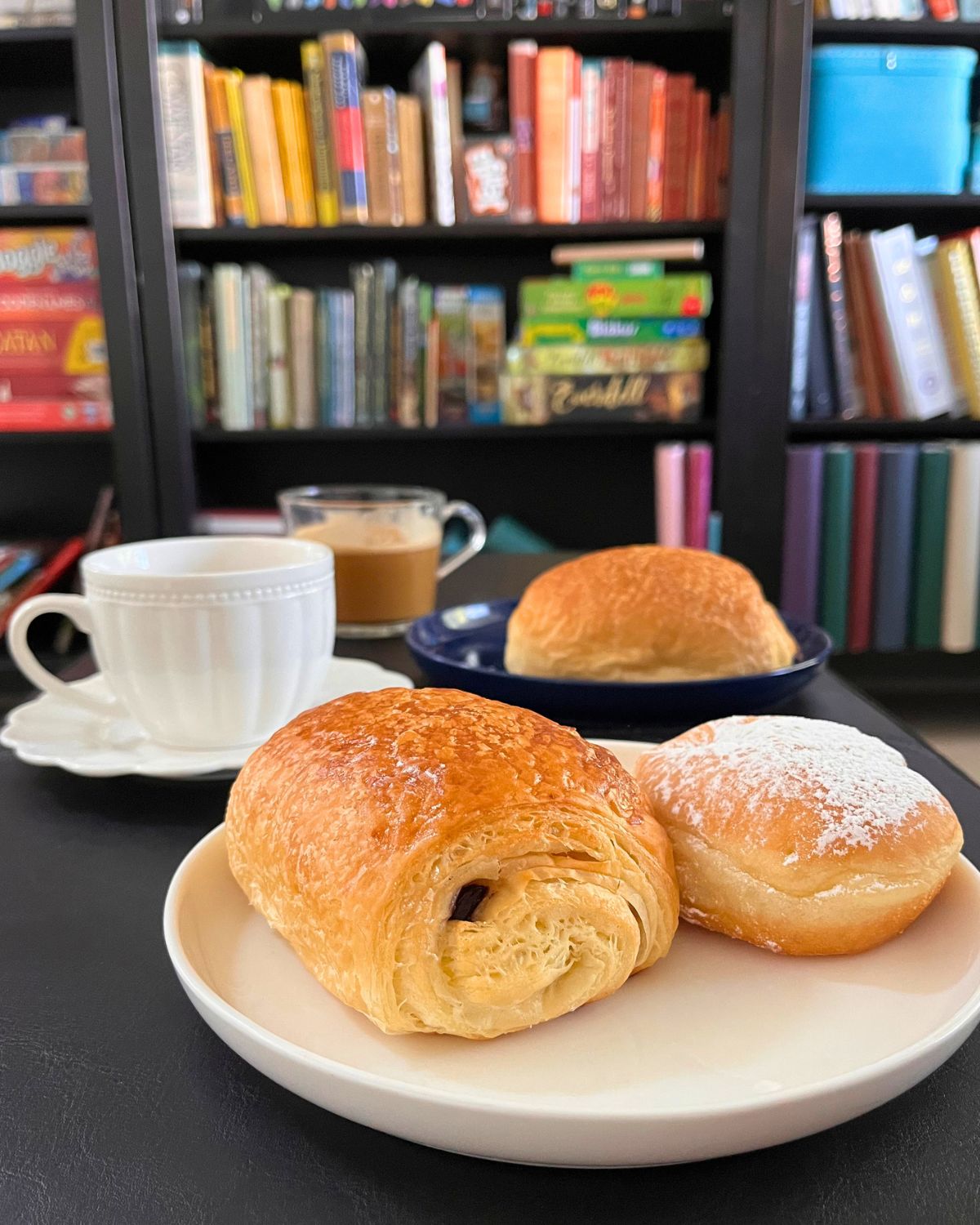 plates of pastries and cups of coffee on ottoman in library.