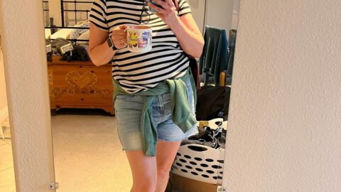jessica dressed in spring outfit with phone and disneyland mug.