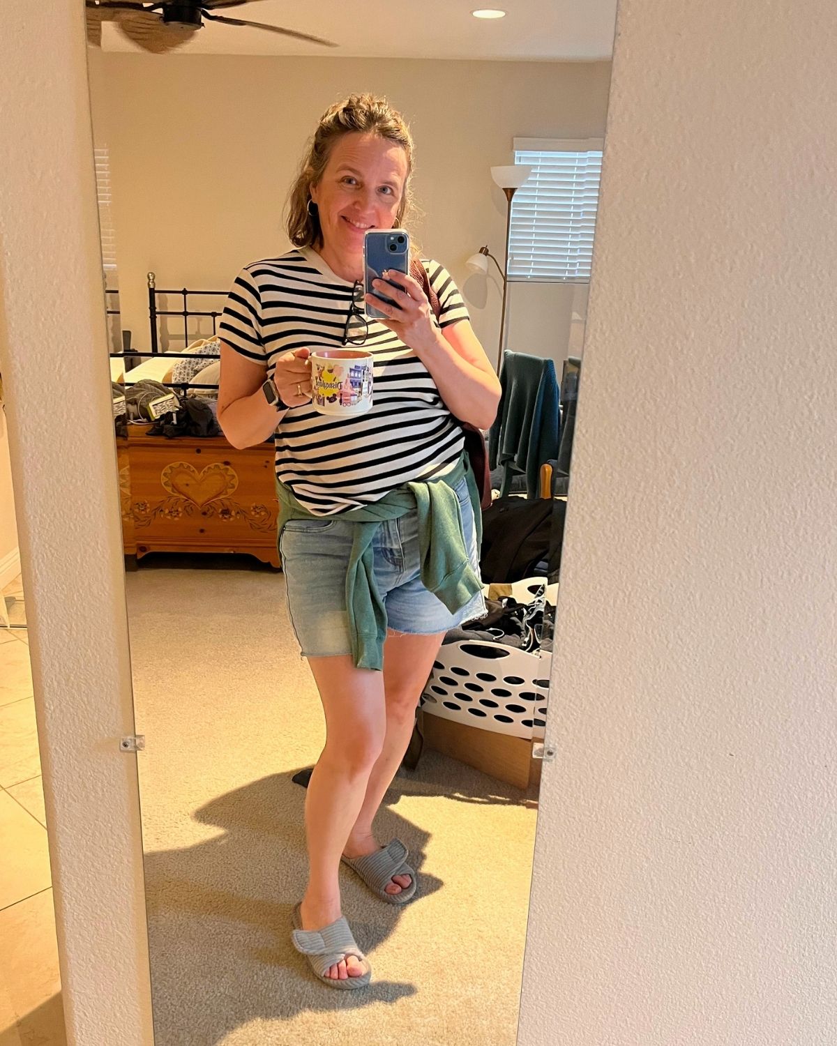 jessica dressed in spring outfit with phone and disneyland mug.