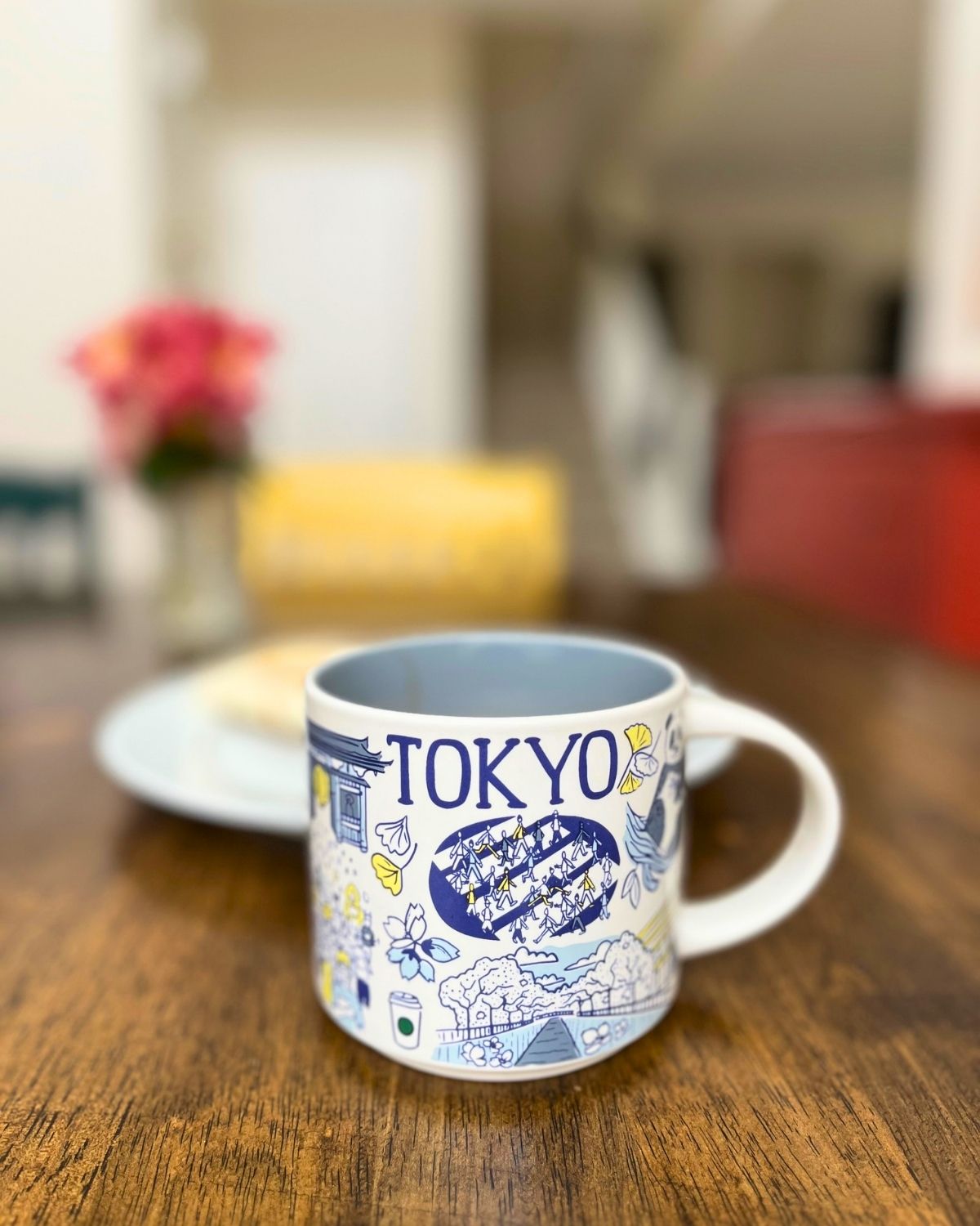 tokyo mug on dining table with plate and vase of flowers in the background.