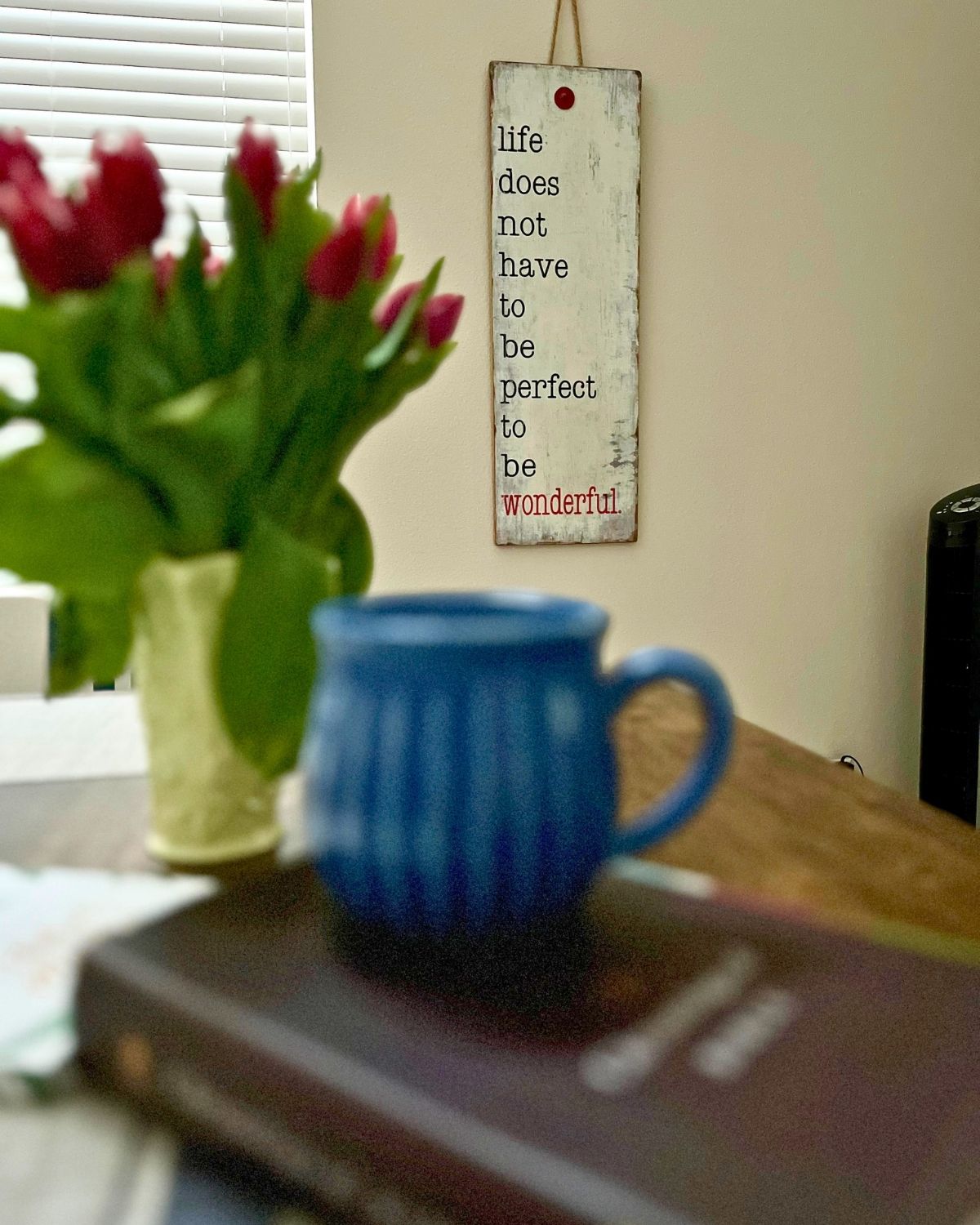 bible, mug, tulips, and a sign near dining table.