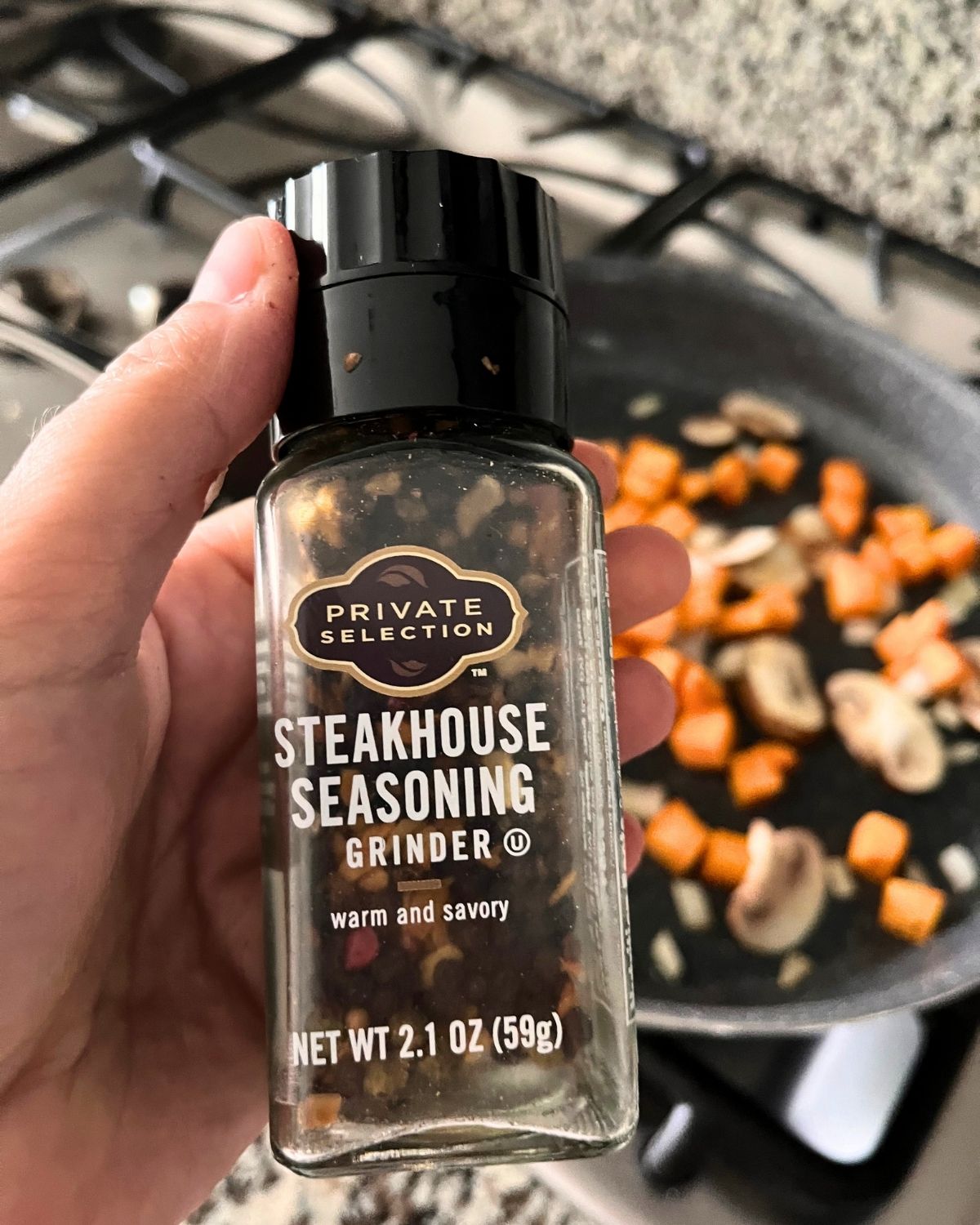 steakhouse seasoning grinder with pan of veg in the background.