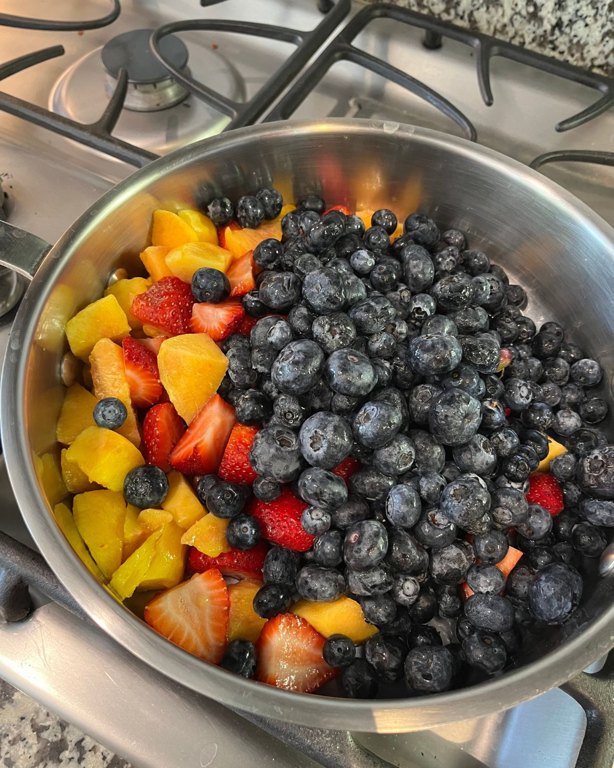 pot of chopped fruit and berries on stove top.