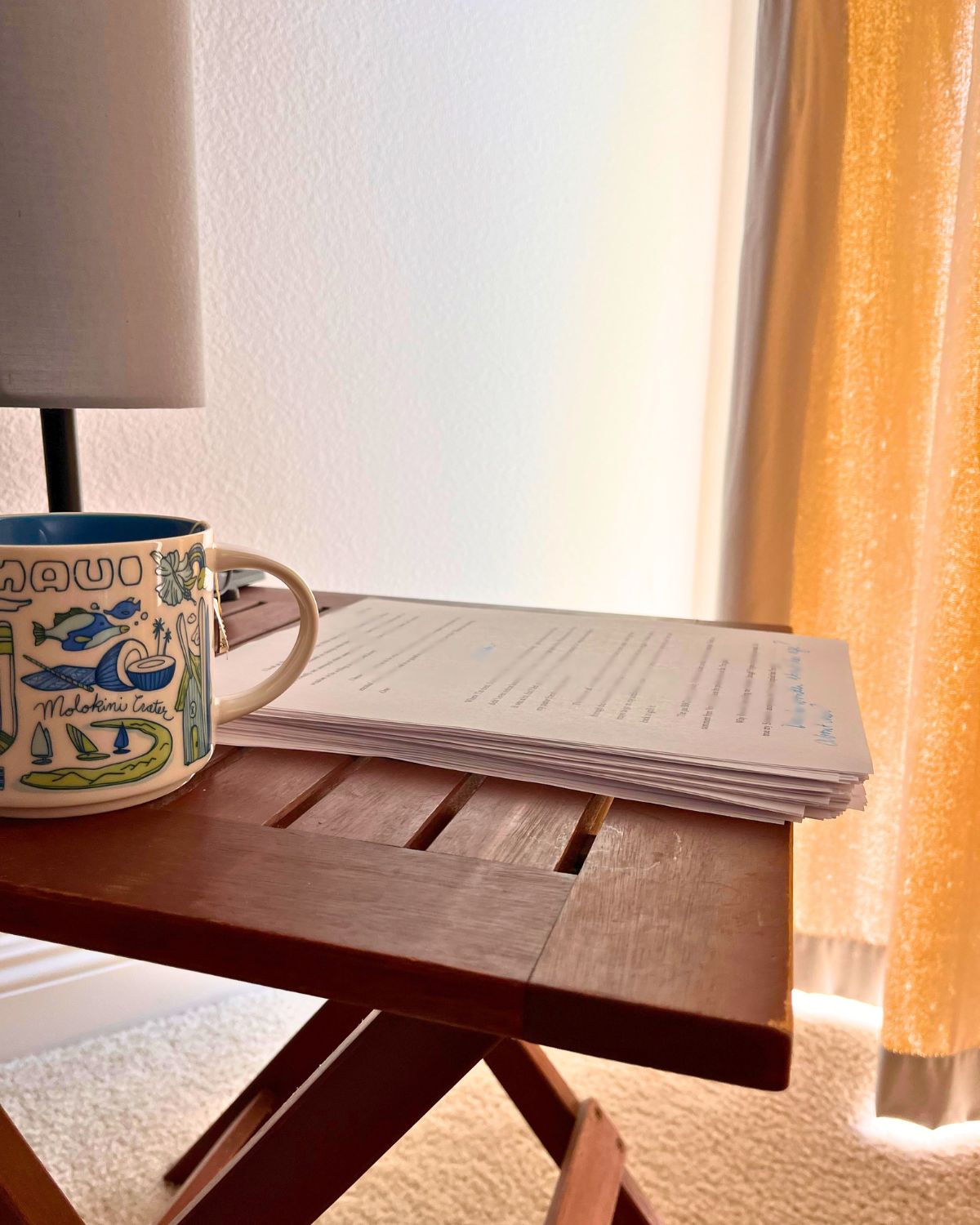 manuscript on wood table with mug and lamp.