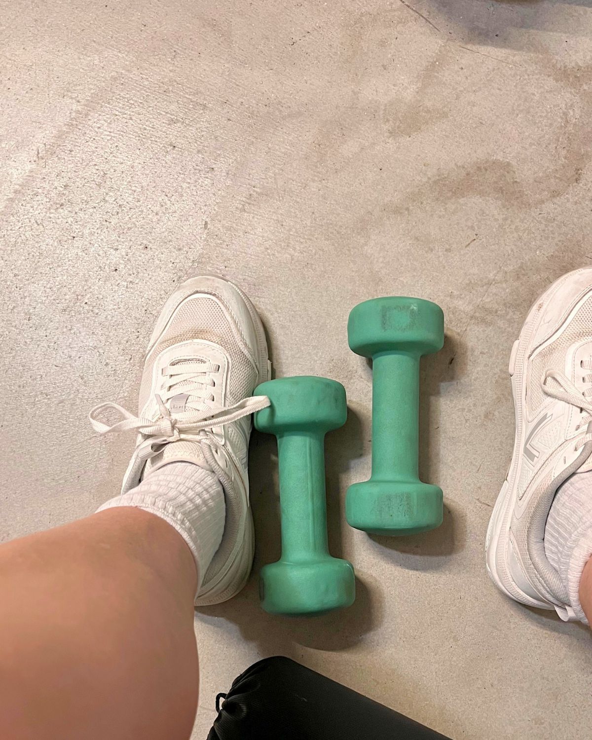 green weights on garage floor between shoe-clad feet.