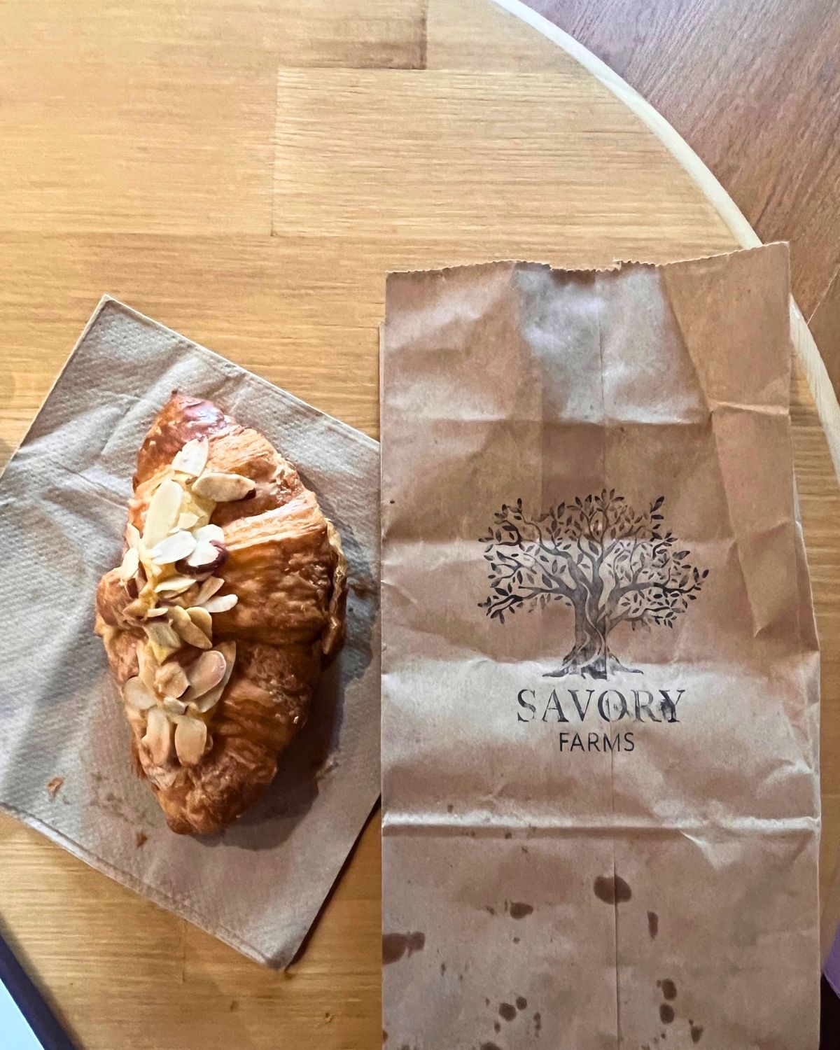 almond croissant on brown napkin next to brown paper bag with the words Savory Farms.