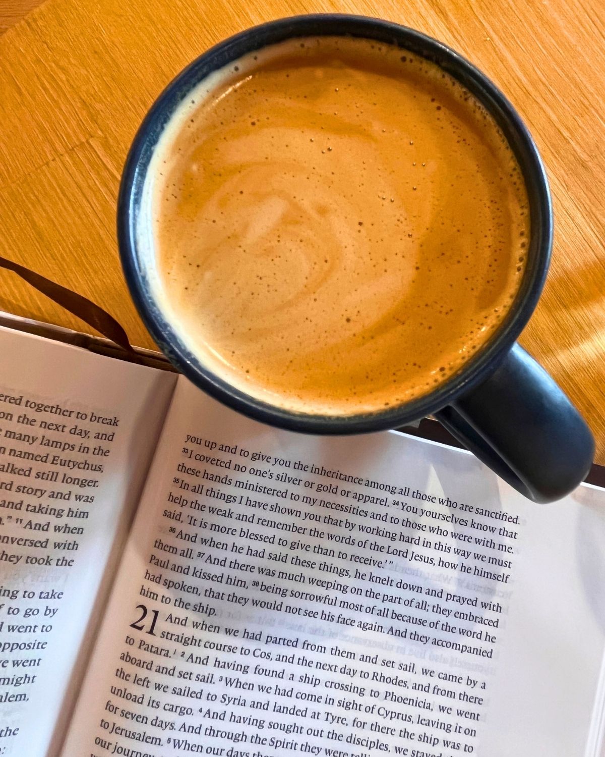 flat white in a mug next to open bible.