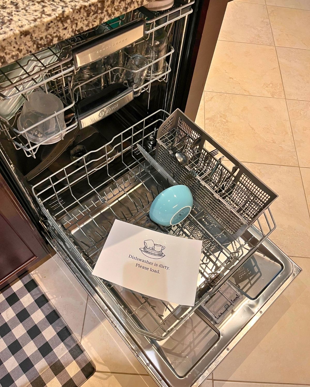 open dishwasher with sign to load one's dishes.
