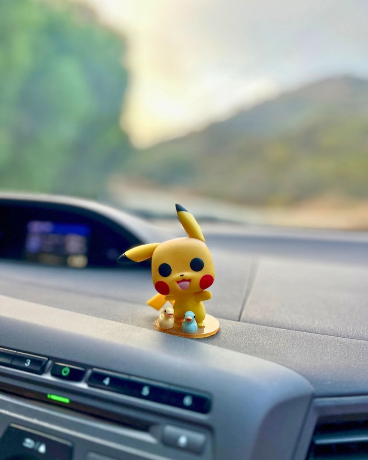 pikachu on dash board of car with mountain in distance.