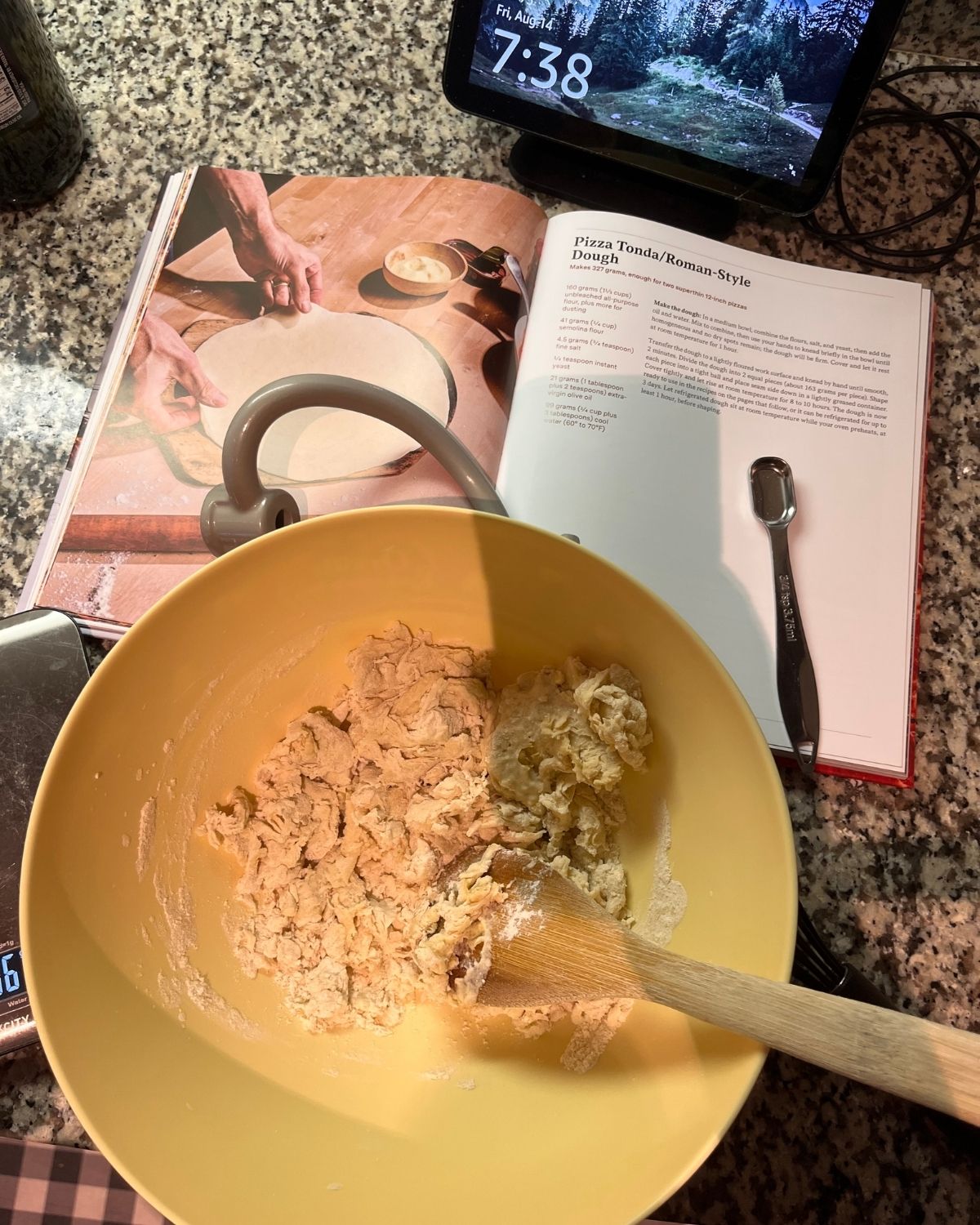 pizza dough by open cookbook on kitchen counter.