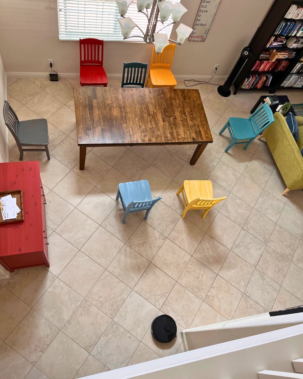 overhead view of chairs pulled away from table with robot cleaning the floors.