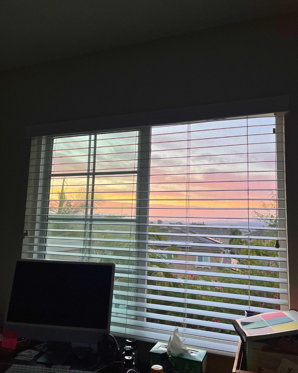 sunrise outside bedroom window, with a desk in the foreground.