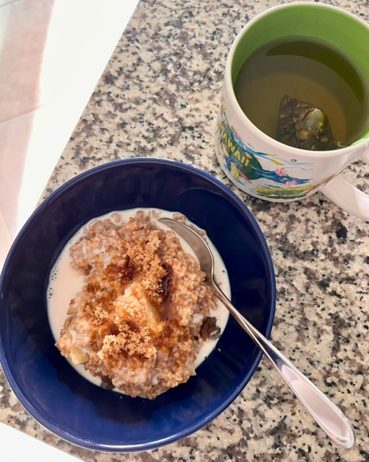 bowl of apple cinnamon oatmeal on counter next to tea.