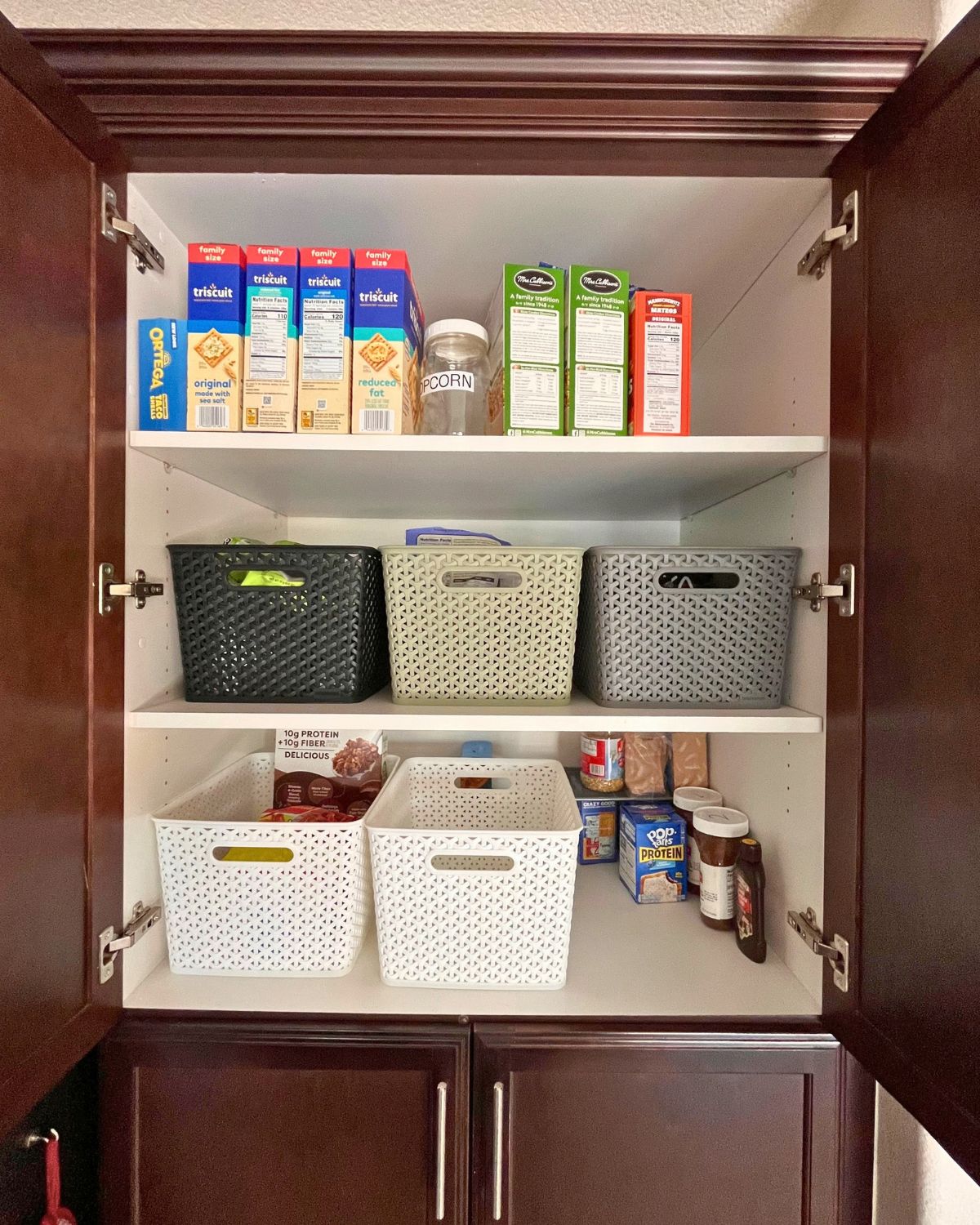 tidied pantry cupboard with bins for the kids.