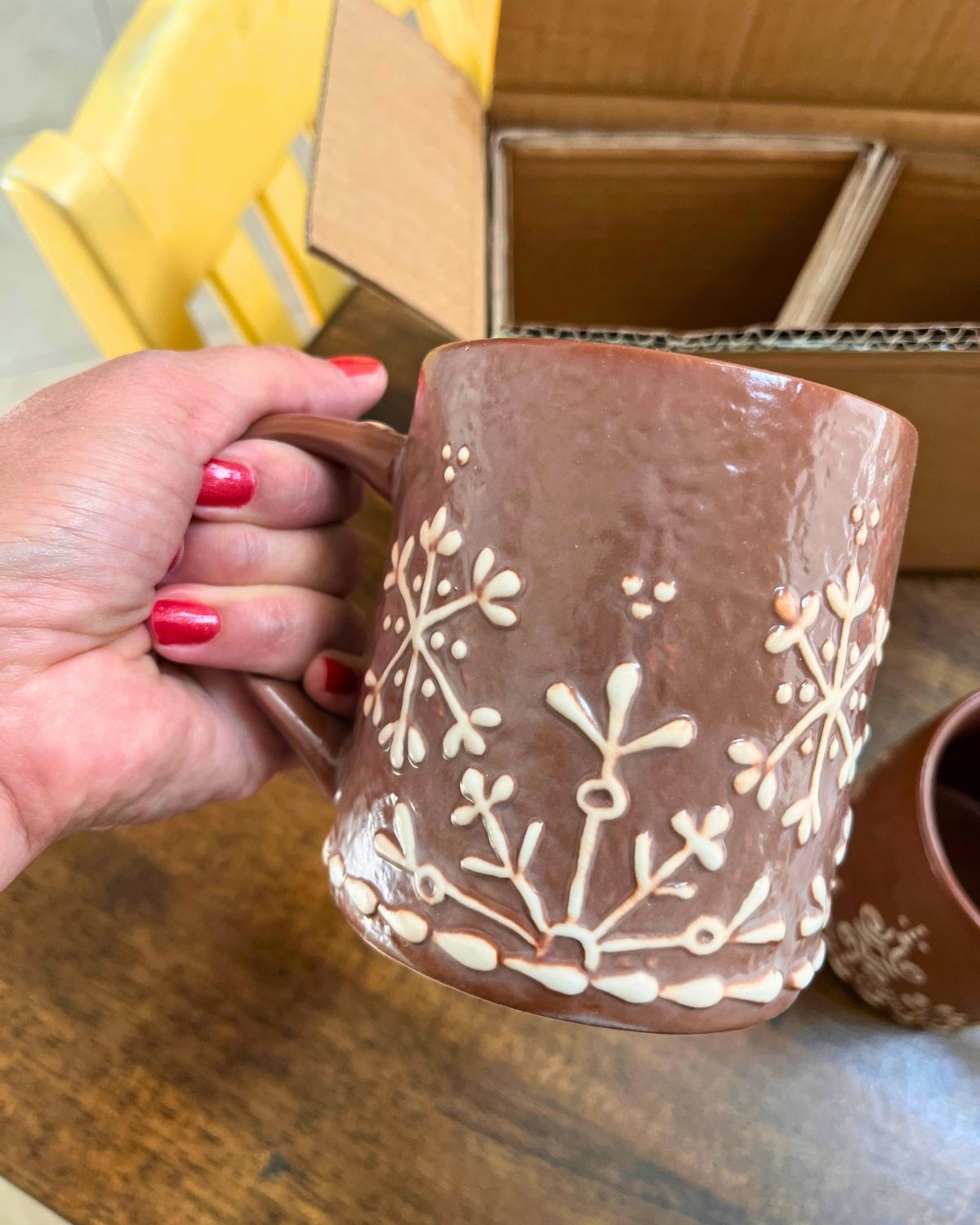 red polish on fingernails of hand holding gingerbread mug.