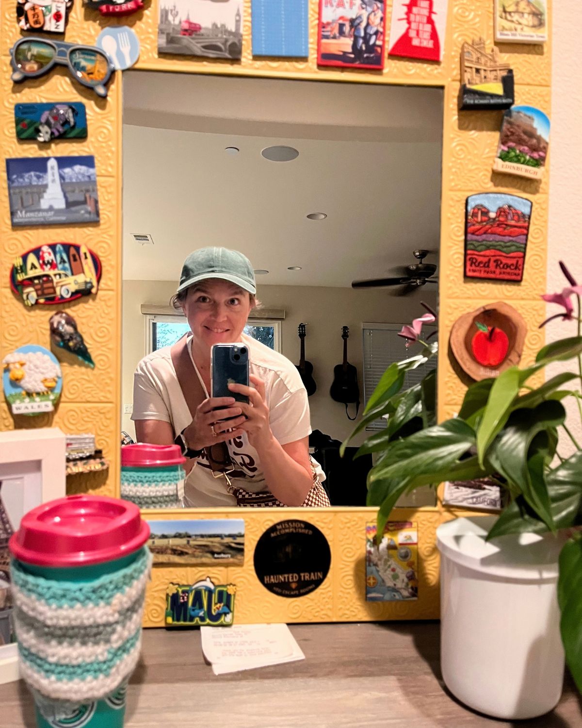 jessica looking in mirror for selfie with tea in cup cozy on shelf.
